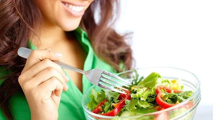 Rapariga a comer salada de vegetais com uma dieta proteica